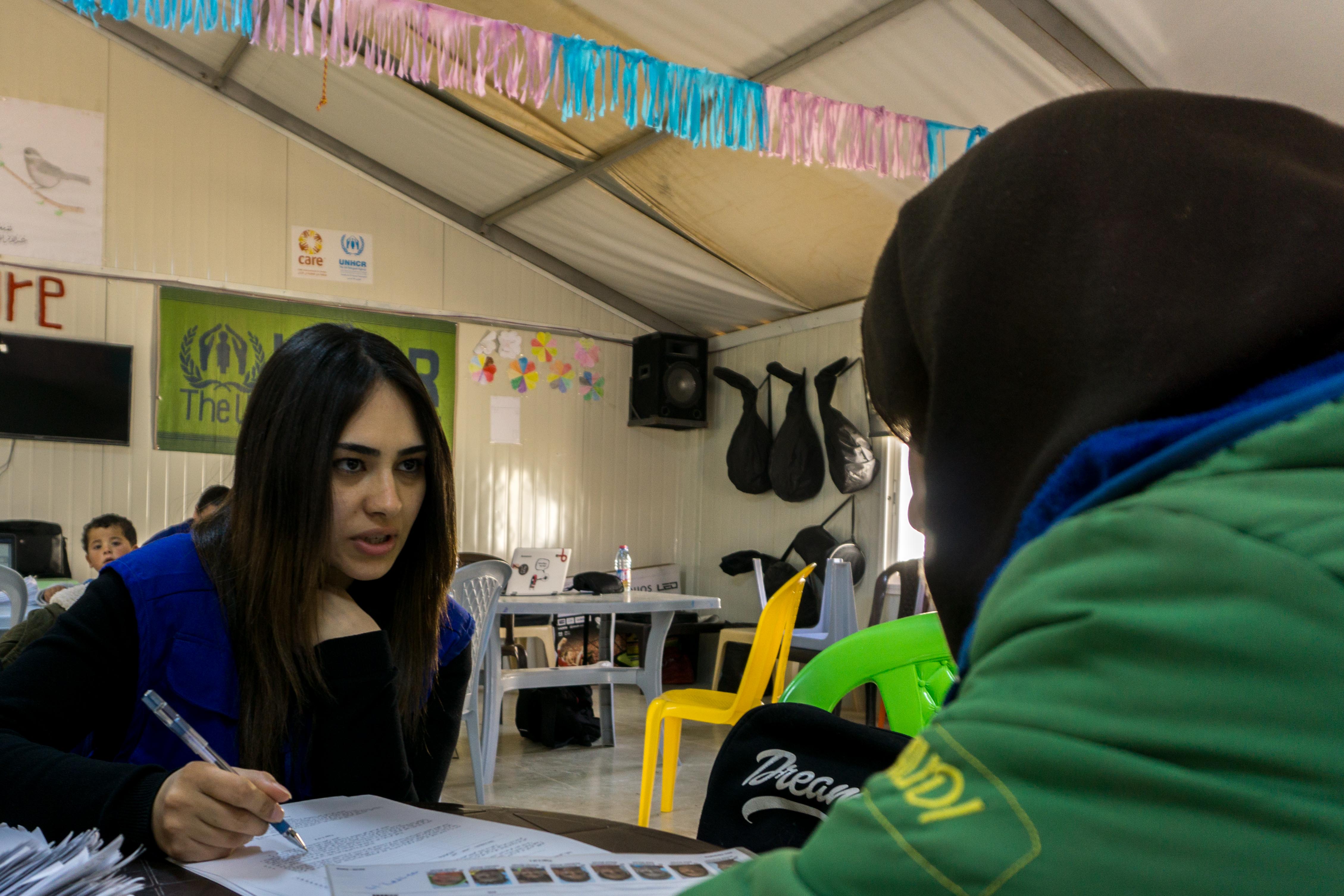 IOM female staff helping a woman refugee with paperwork
